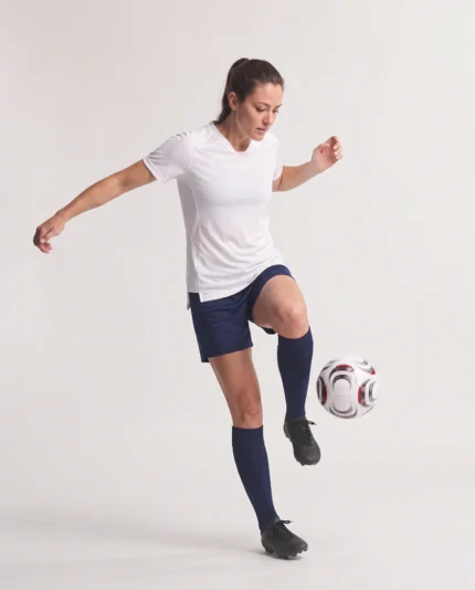 Woman wearing the white Ladies Hawk Evolution Soccer Jersey while controlling a soccer ball.