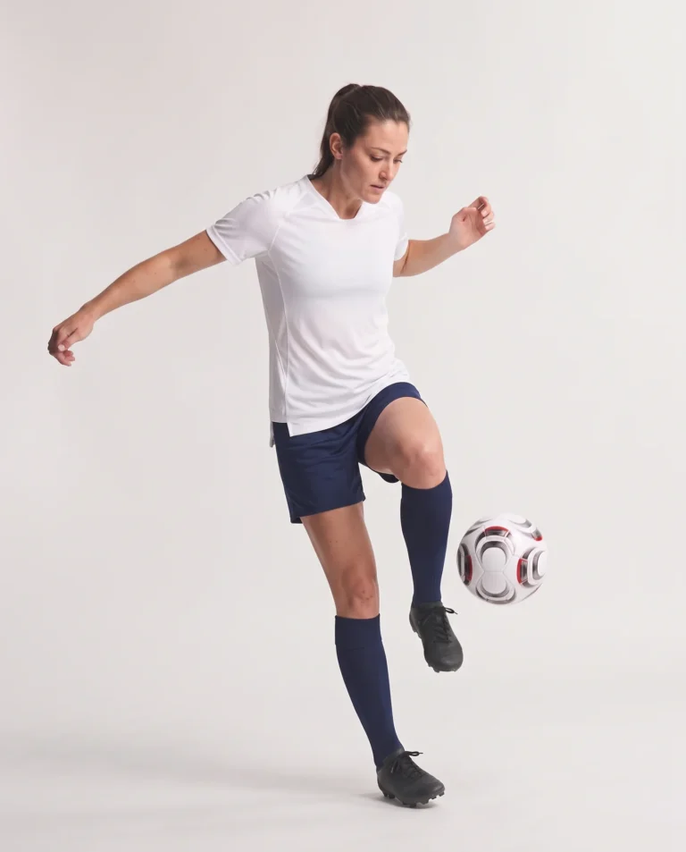 Woman wearing the white Ladies Hawk Evolution Soccer Jersey while controlling a soccer ball.